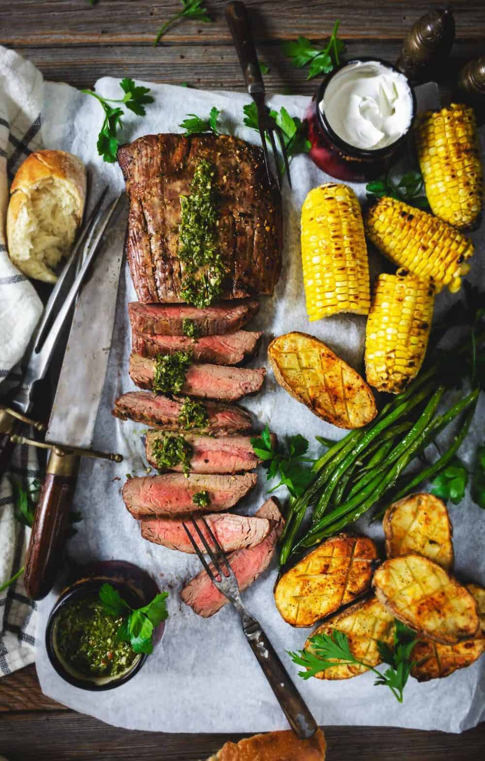 A flat lay of grilled steak with vegetables on a sheet pan