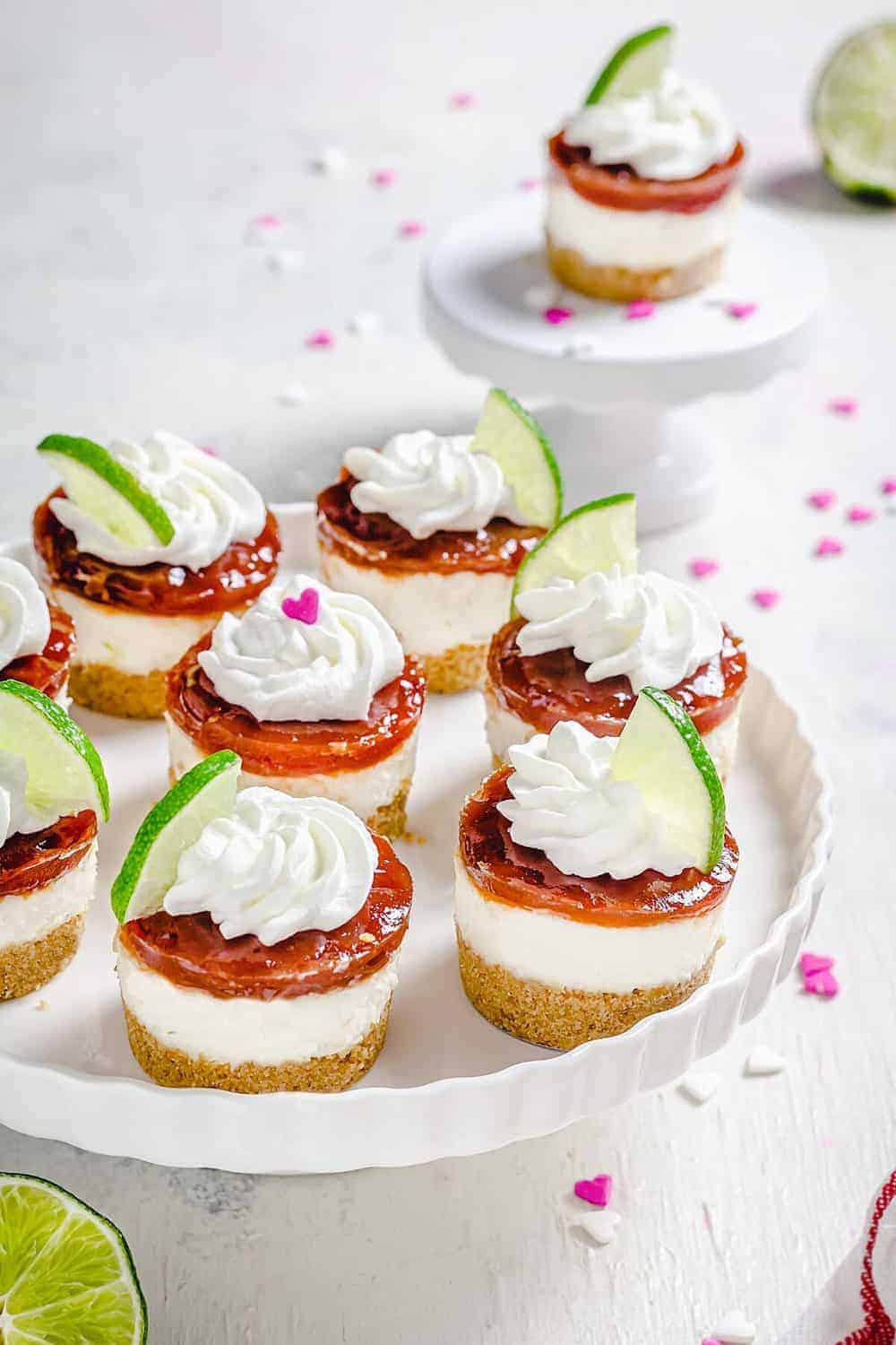 Mini cheesecakes sitting on a cake stand sitting on a white table.