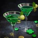 Two martini glasses with green cocktail on a black background.