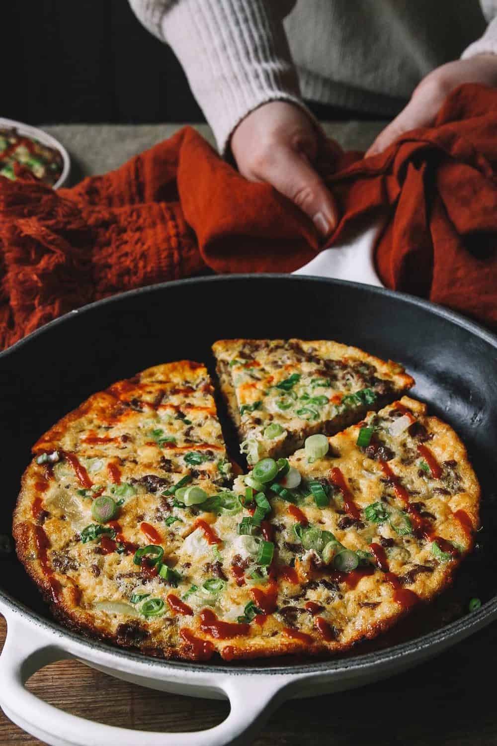 A person serving omelette in a skillet.