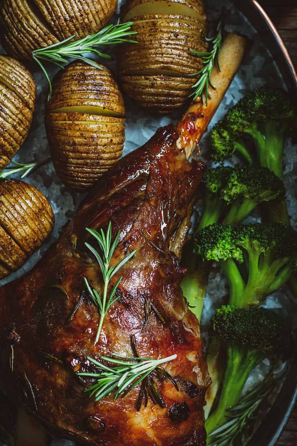 Close up of roasted leg of lamb with broccoli and Hasselback potatoes.
