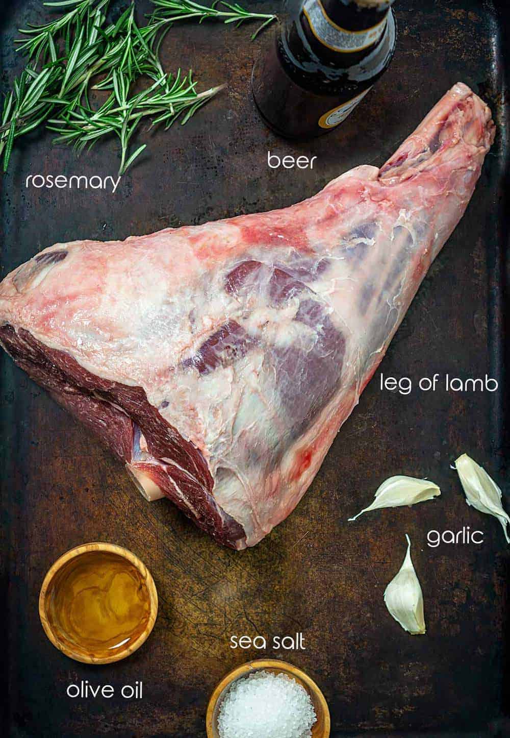 Ingredients for lamb roast with lamb leg, rosemary, garlic, salt, and beer.