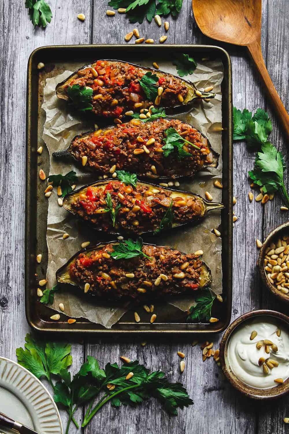 Lamb and pine nuts stuffed eggplant halves lined up on a baking sheet.