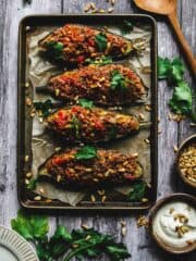 Lamb and pine nuts stuffed eggplant halves lined up on a baking sheet.