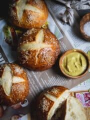 Overhead shot of pretzel rolls on a German papers with salt and mustard.