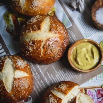 Overhead shot of pretzel rolls on a German papers with salt and mustard.