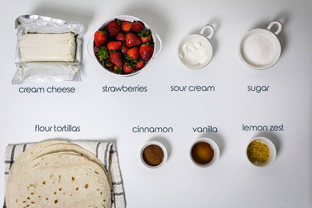 Ingredients for xangos on a counter with tortillas, cream cheese, and fresh strawberries.