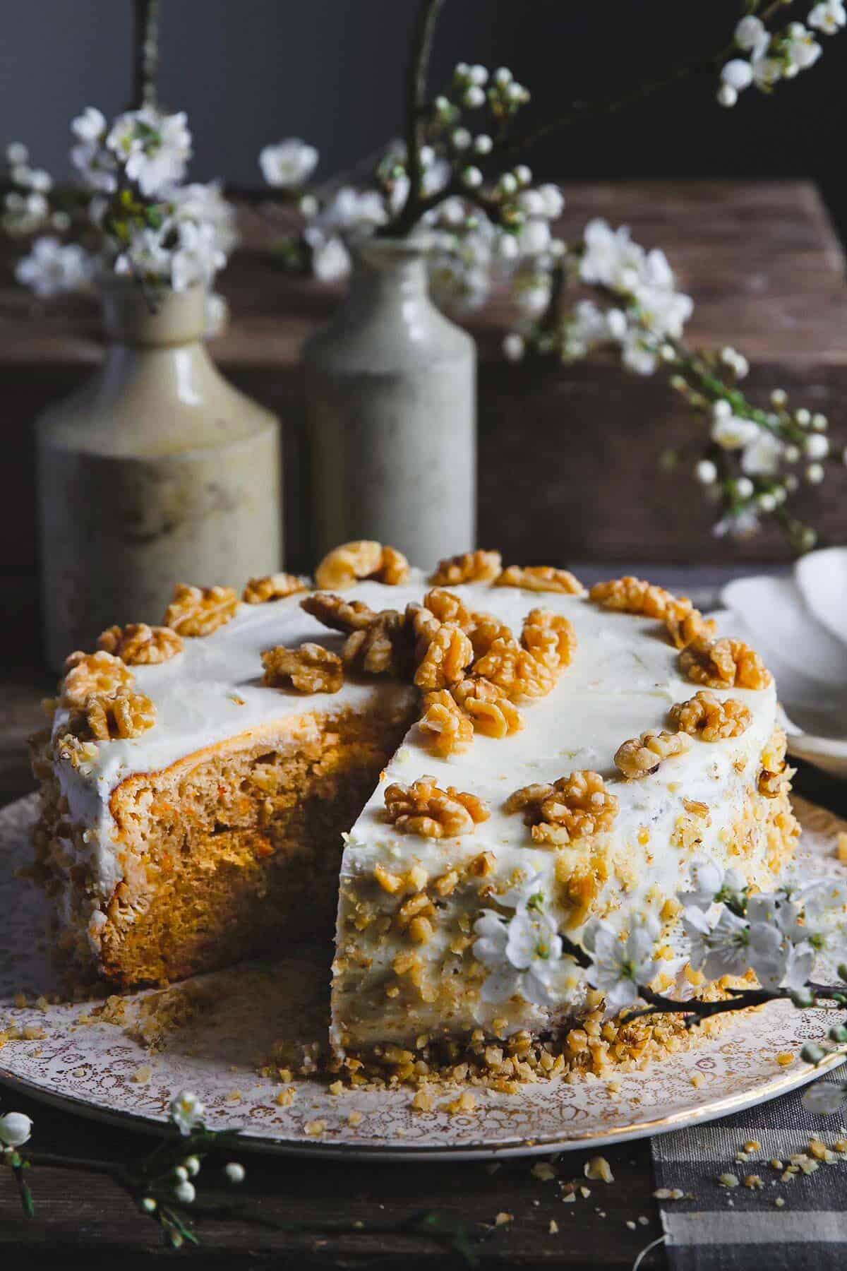 Carrot cake cheesecake on a cake stand with one slice removed.