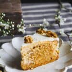 A close up of a carrot cake cheesecake slice on a white plate.