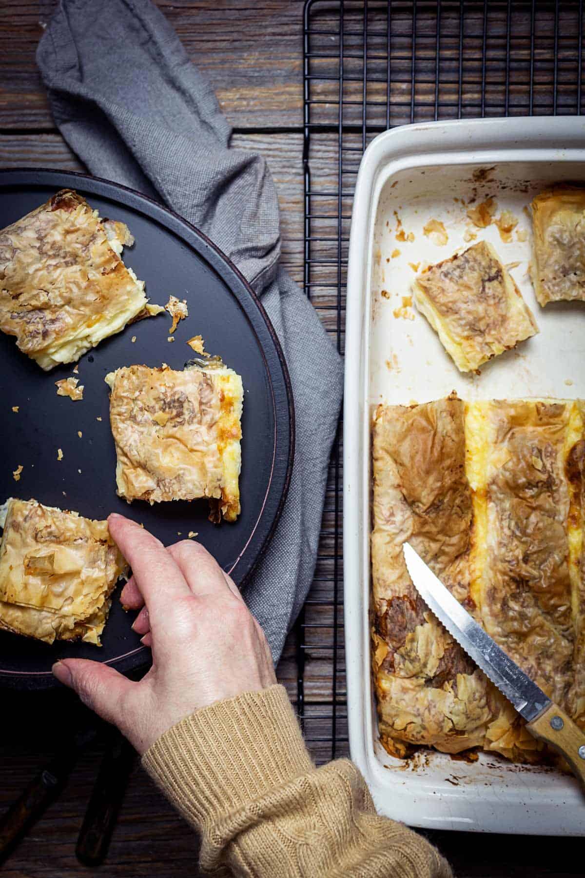 A person grabbing a piece of savory cheese pie.