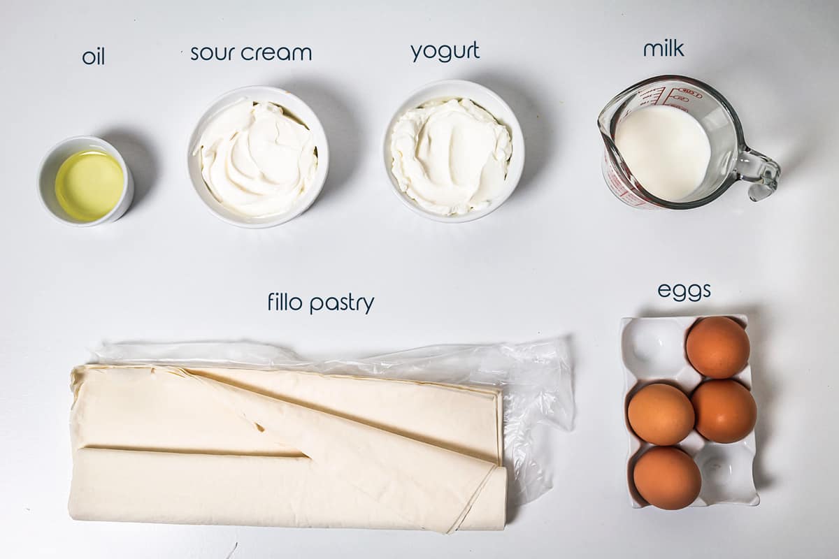 Ingredients for the egg pie with fillo eggs, sour cream, and yogurt on the counter.