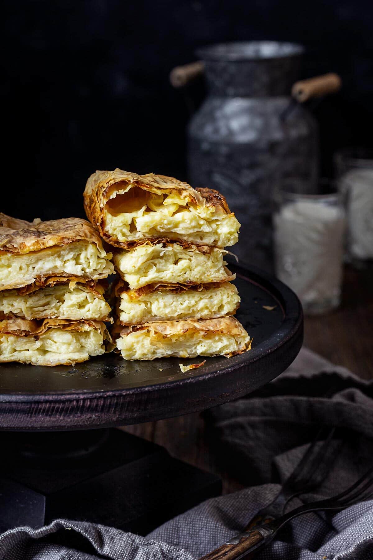 Stacks of cheese pie pieces on a black stand.