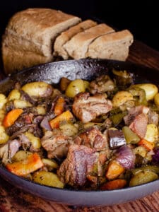 Peka stew with meat and vegetables in a skillet with bread.