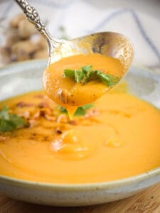 Grabbing peanut butter soup in a bowl with a spoon.