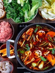 A pot with Japanese soup with vegetables, beef, and noodles.