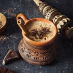 Overhead shot of Oaxacan hot chocolate in a clay mug with cinnamon stick.