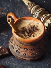 Overhead shot of Oaxacan hot chocolate in a clay mug with cinnamon stick.