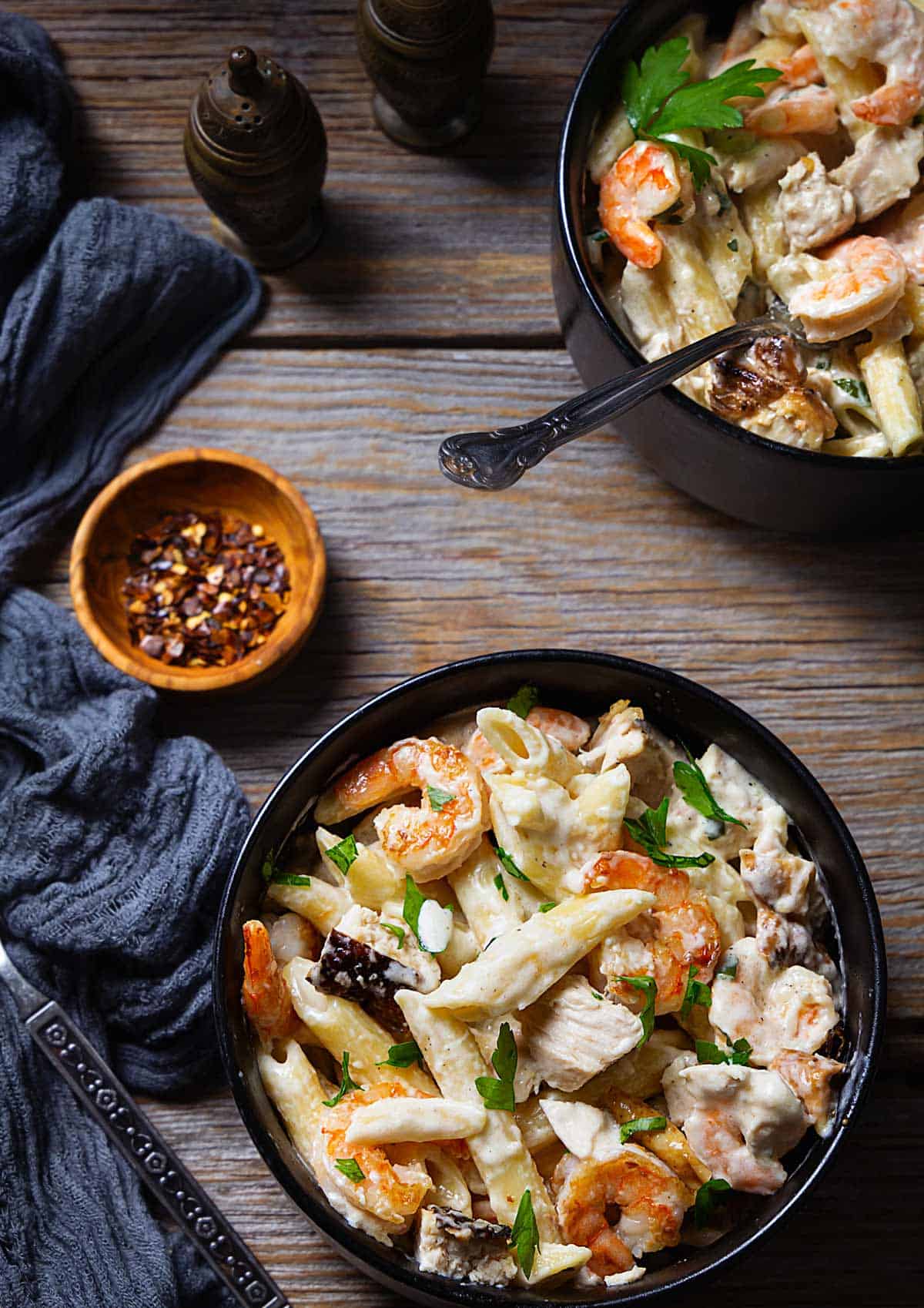 Two bowl with alfredo penne sitting on a wooden table. 