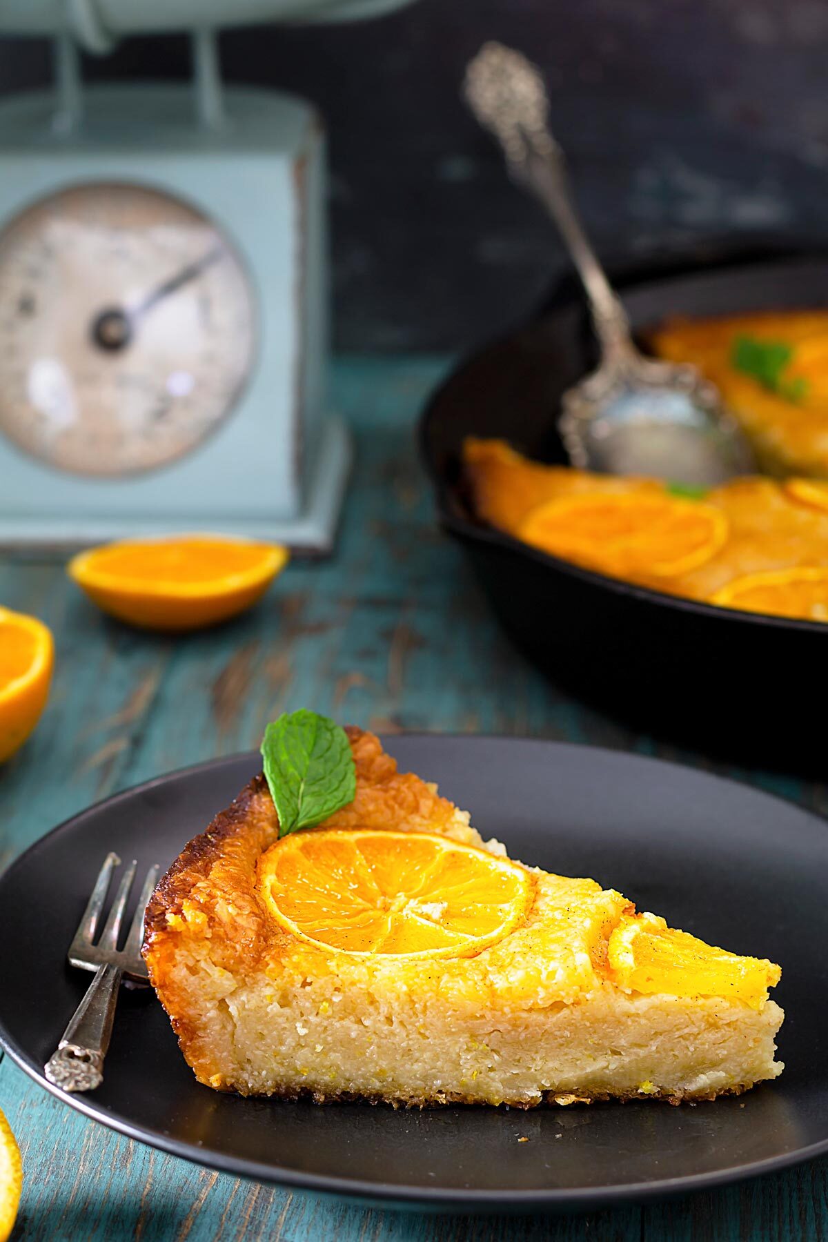 A close up of a served fillo cake with citrus on a black plate.