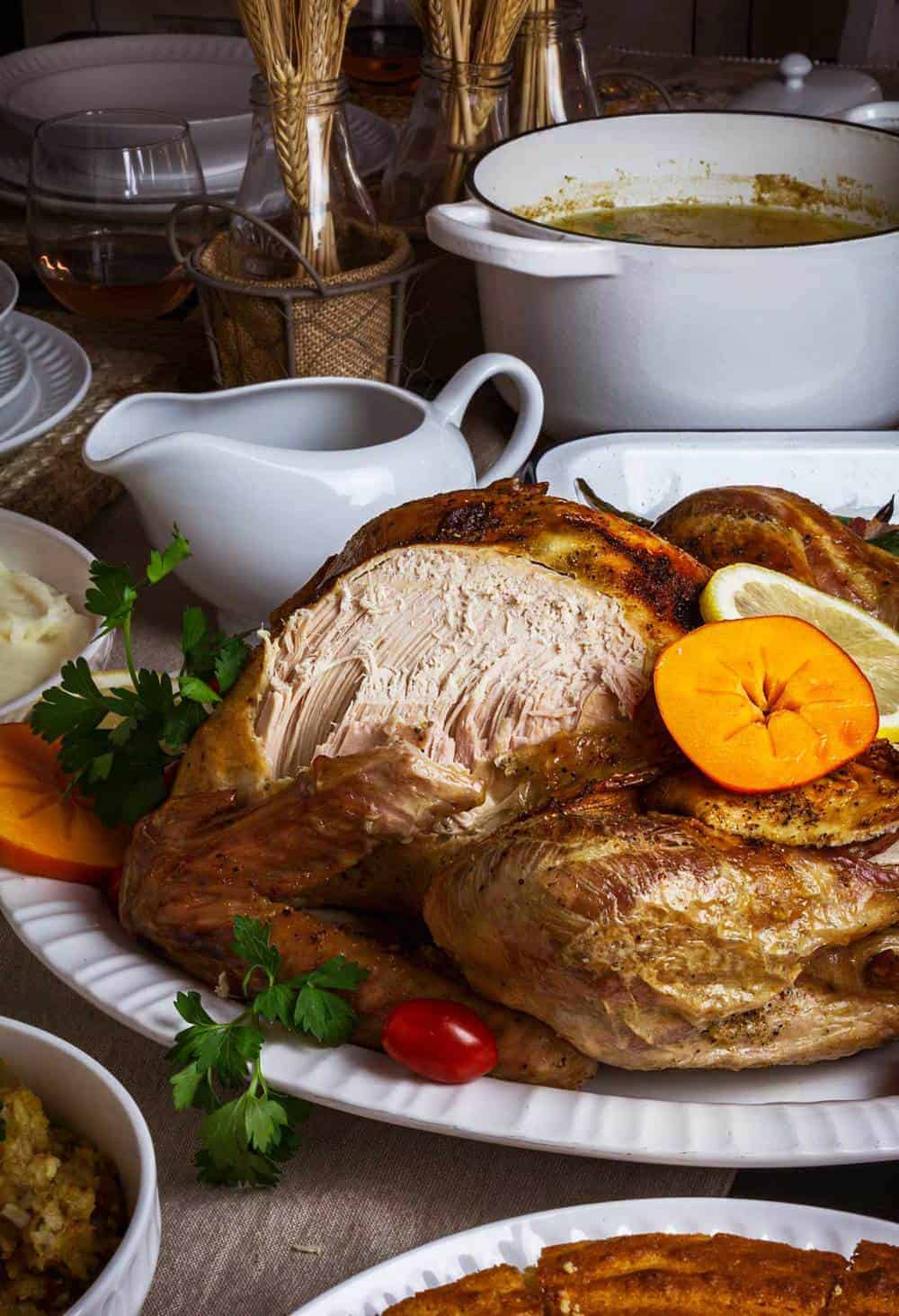 Side shot of turkey roast with a portion of the breast cut off and surrounded by side dishes.