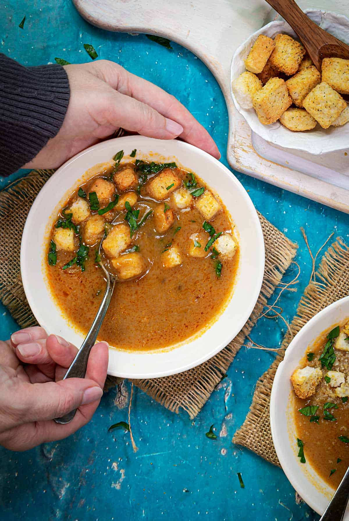 A person scooping up roux soup from a bowl with a spoon.