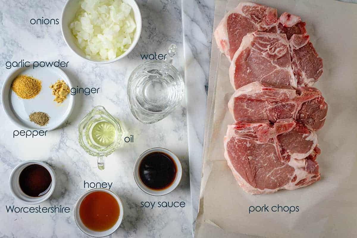 Ingredients for pork chops with honey glaze including the meat, spices, and onions.