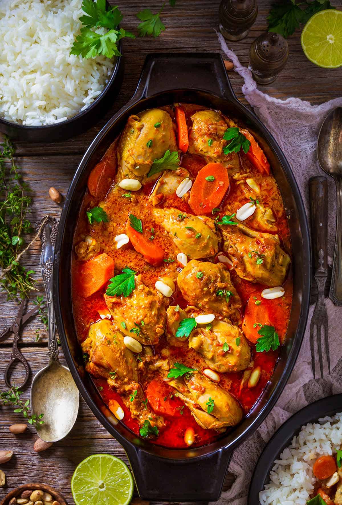 African peanut stew with chicken drumsticks in an oval dish on a table with white rice.