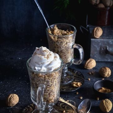 Two glasses with whole wheat berry pudding on a table, with walnuts and whipped cream.