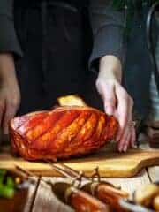 A person placing the pork roast on a table.