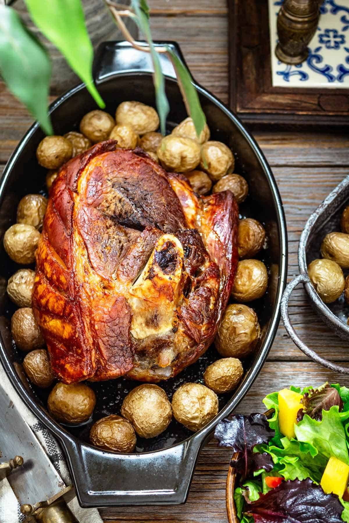 Boston butt in a dish with baked potatoes.