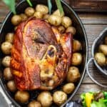 Boston butt in a dish with baked potatoes.