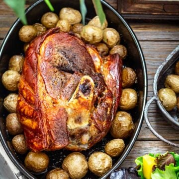 Boston butt in a dish with baked potatoes.