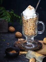 A close up glass dish with wheat berry pudding topped with whipped cream.