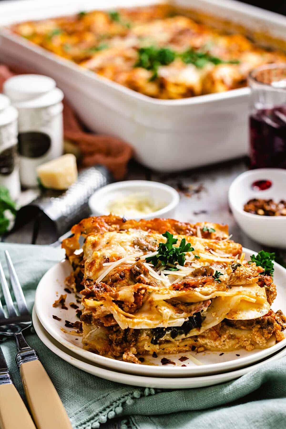 Slice of Sicilian lasagna plated on a table with the pan in the background. 