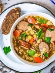 A bowl of German Graupensuppe in a bowl with barley and smoked sausage - featured square image