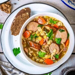 A bowl of German Graupensuppe in a bowl with barley and smoked sausage - featured square image