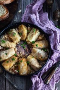 Overhead photo of a plate with rolls on a wooden table with purple napkin.