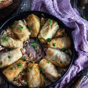 Overhead photo of a plate with rolls on a wooden table with purple napkin.