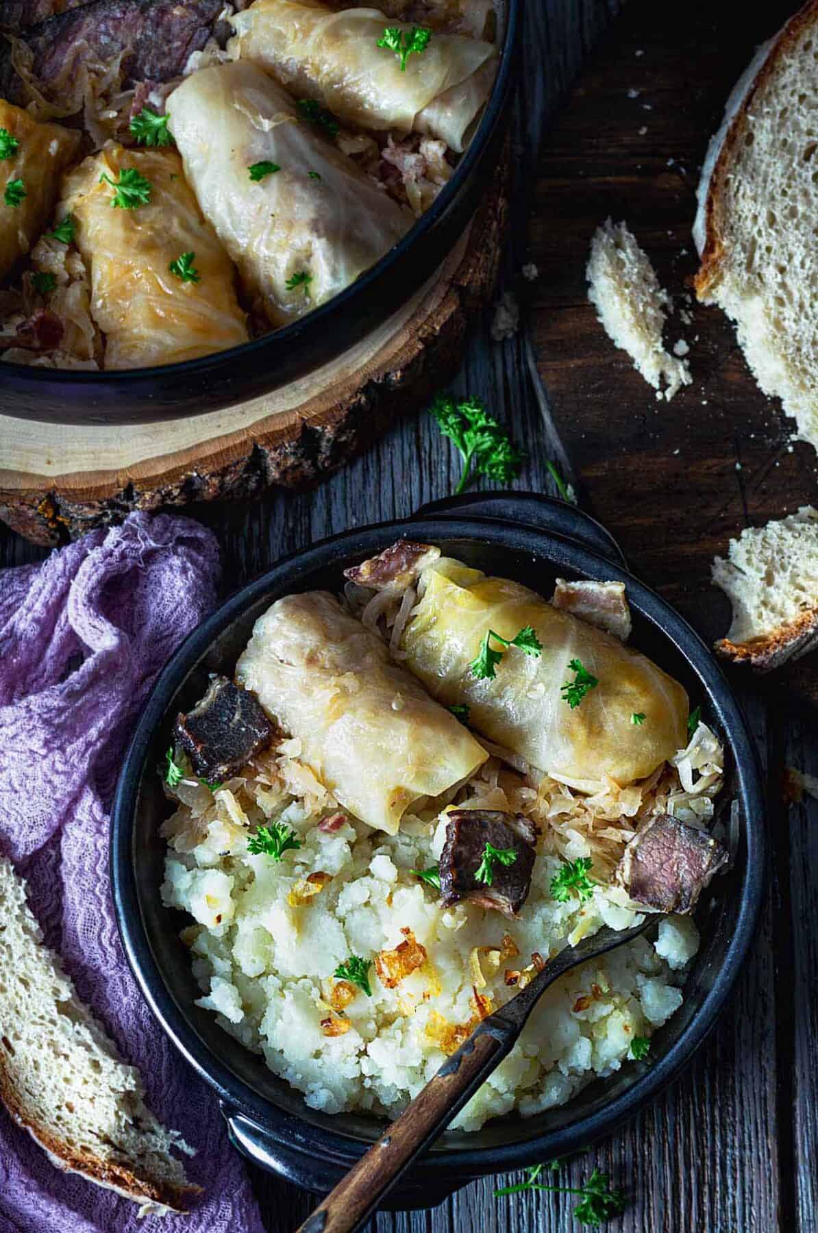 An overhead view of two cabbage rolls on a plate with mashed potatoes and a spoon.