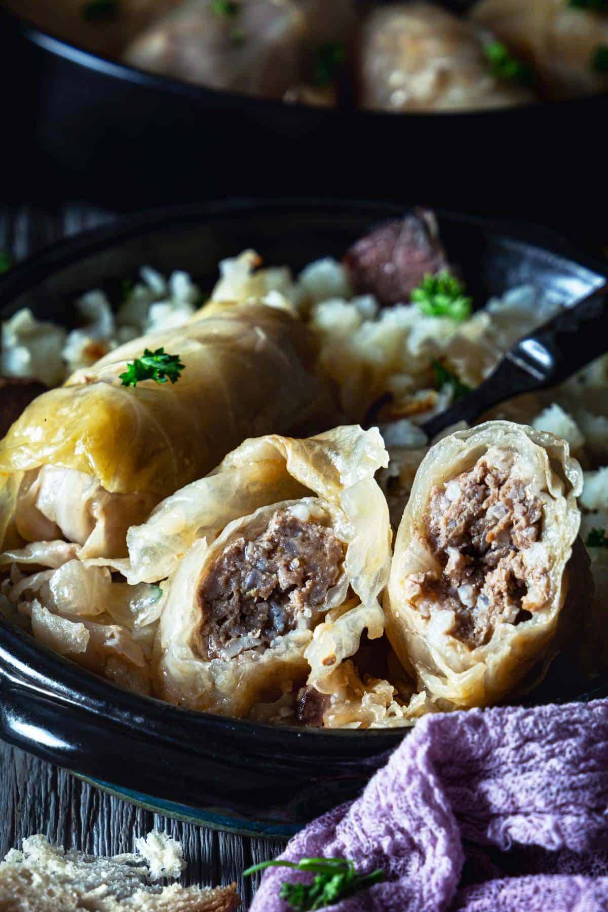 A close up of the cabbage roll cut in half showing the ground beef filling inside.