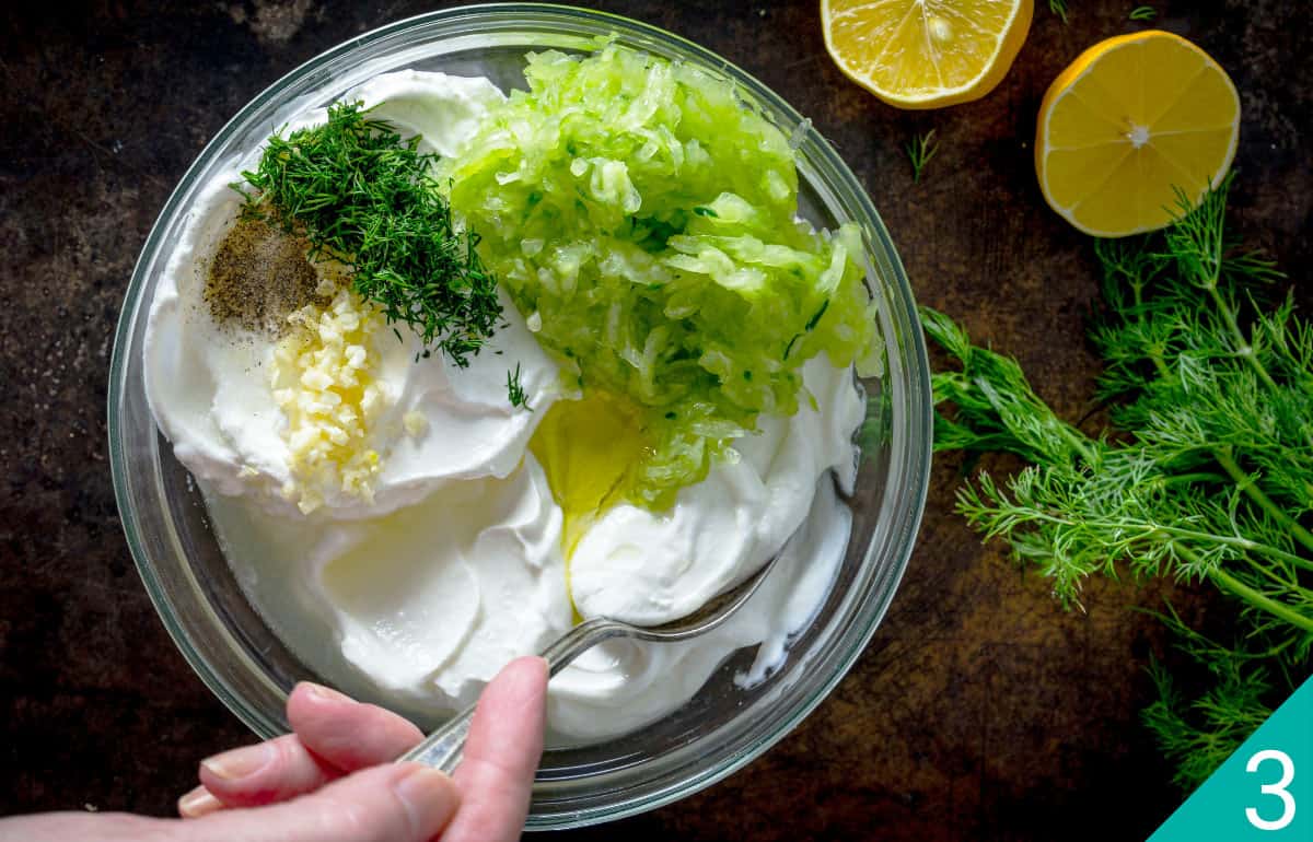 Mixing cucumber, garlic, lemon juice, dill, and sour cream with yogurt and oil.