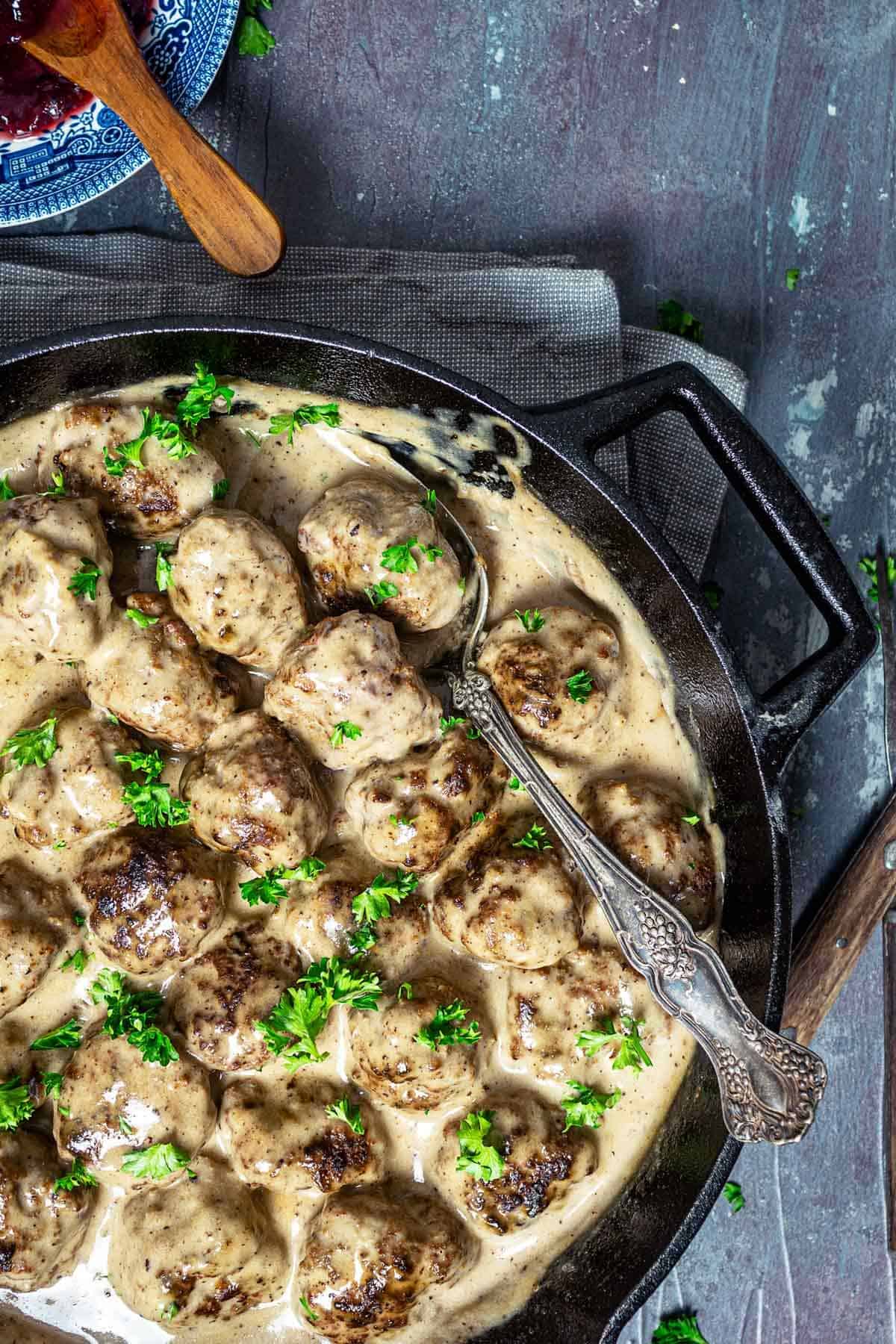 A close up of kӧttbullar in cream sauce with a spoon.