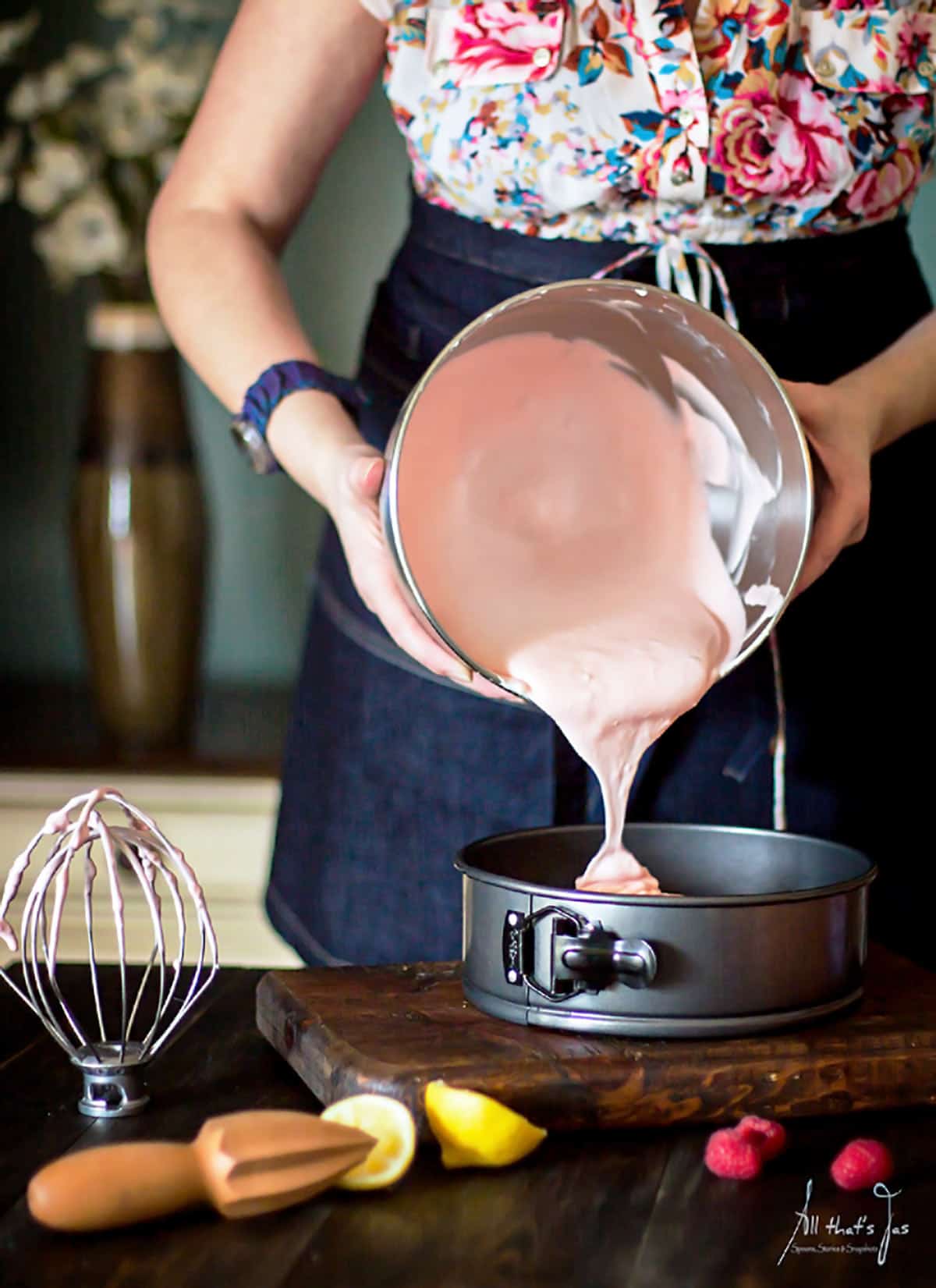 A woman pouring cheesecake batter into a springform.