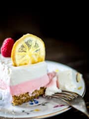 A slice of lemon raspberry cheesecake with candied lemon slice on top.