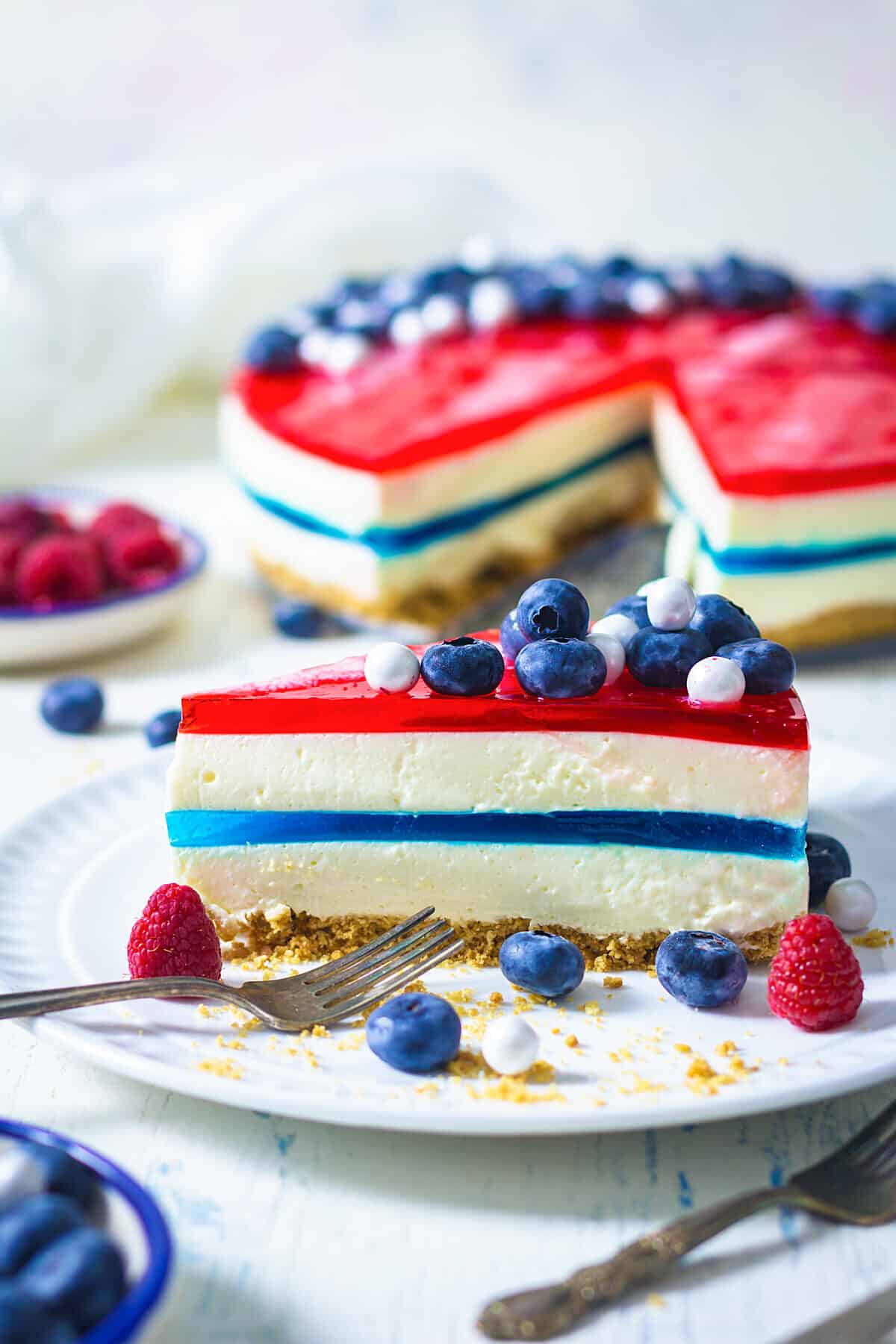 A slice of fresh cake showing off the blue middle layer and the red top with berries.