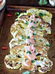 Cauliflower slices with pepper aioli drizzled over them.