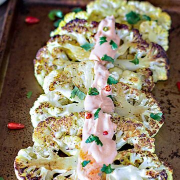 Cauliflower slices with pepper aioli drizzled over them.