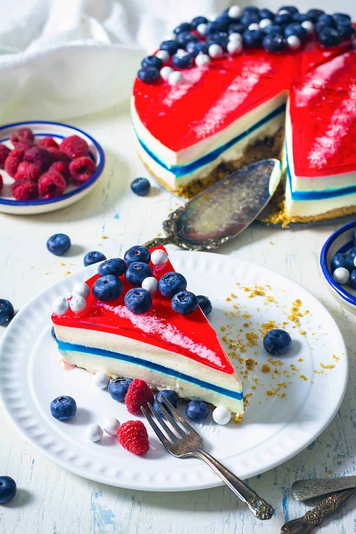 A slice of patriotic gelatin cheesecake on a white plate with fork.