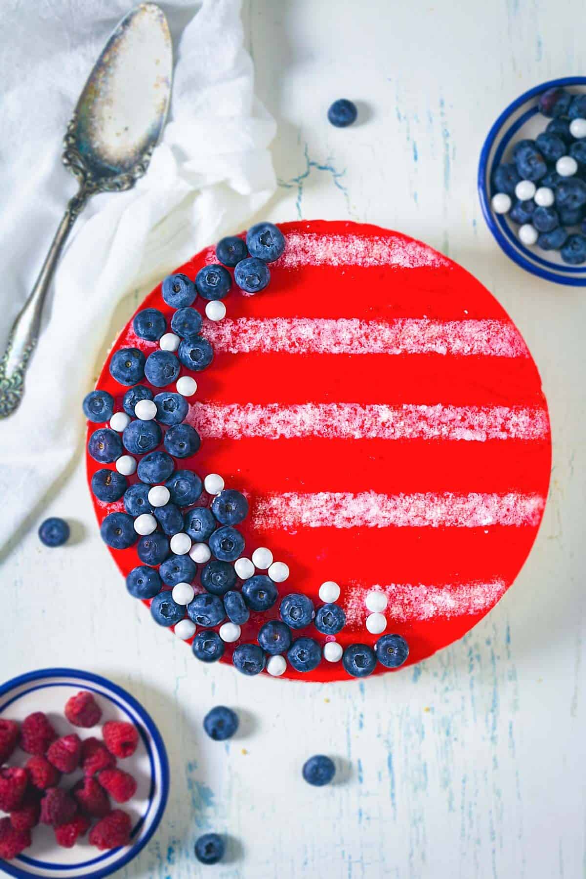 Overhead shot of red white and blue jello cheesecake showing the red top layer with blueberries and white stripes.