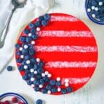 Overhead shot of red white and blue jello cheesecake showing the red top layer with blueberries and white stripes.